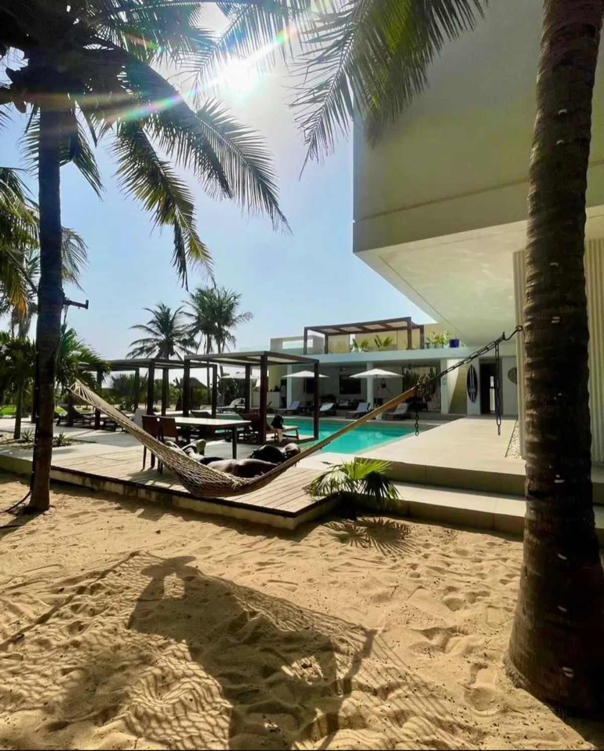 Hammock between palm trees beside a beach house pool